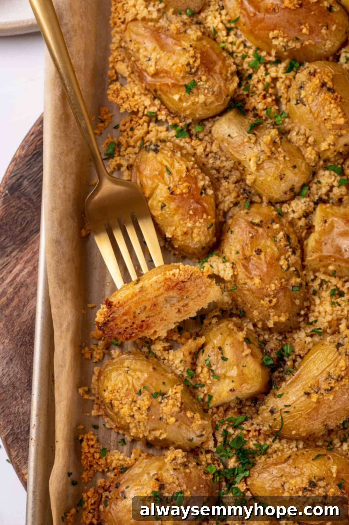 Crispy, cheesy vegan Parmesan crusted potatoes fresh from the oven, on a baking sheet. Parmesan-crusted potatoes on baking sheet with a fork, showing crispy texture