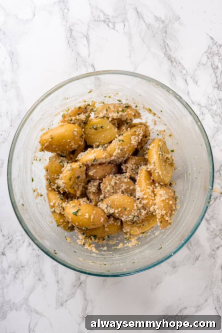 Baby potatoes tossed with melted vegan butter and seasonings in a bowl. Potatoes in a bowl with seasonings and melted butter