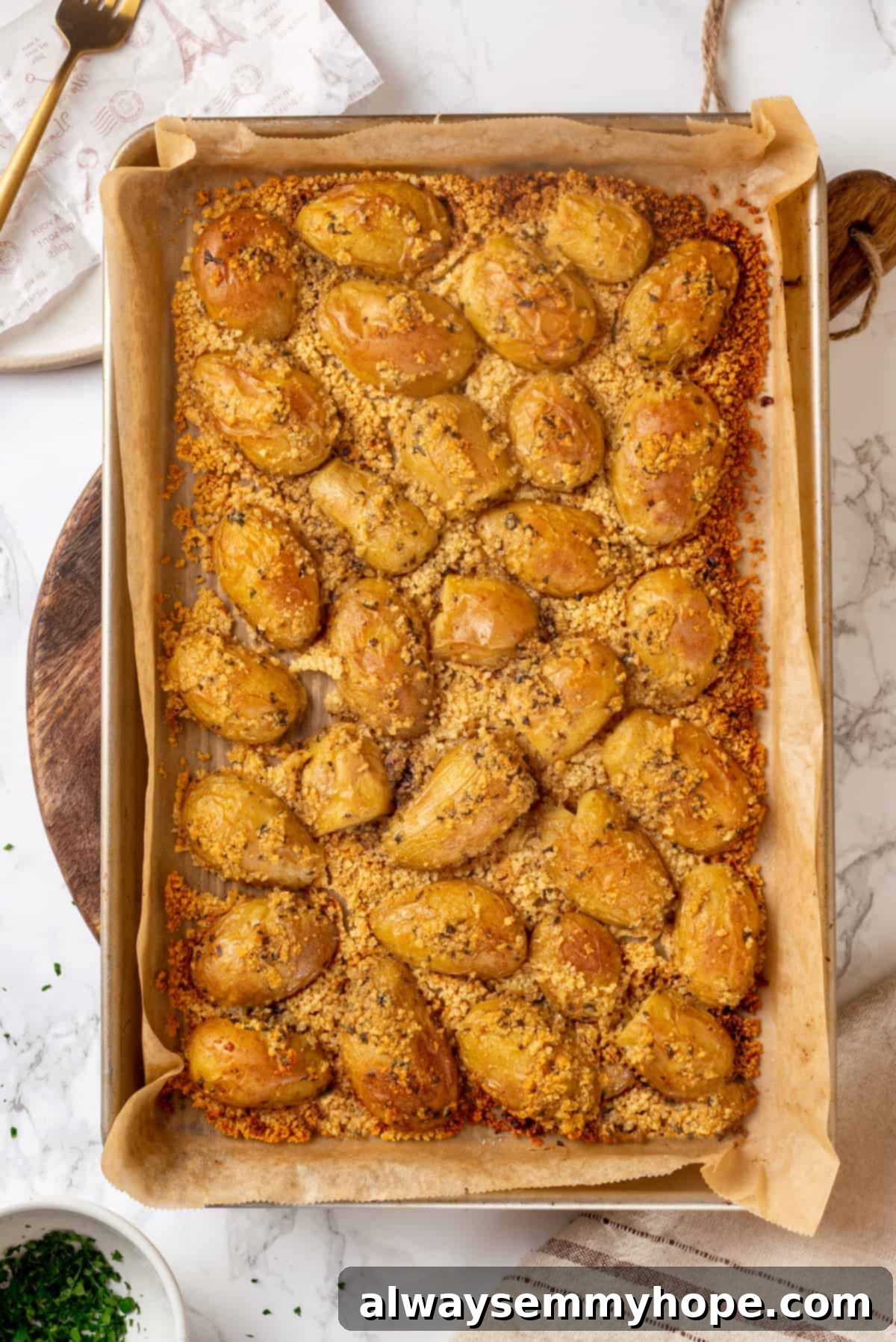 Freshly baked vegan Parmesan crusted potatoes, golden and crispy on the baking sheet. Overhead view of baked Parmesan-crusted potatoes on a baking sheet, golden and crispy