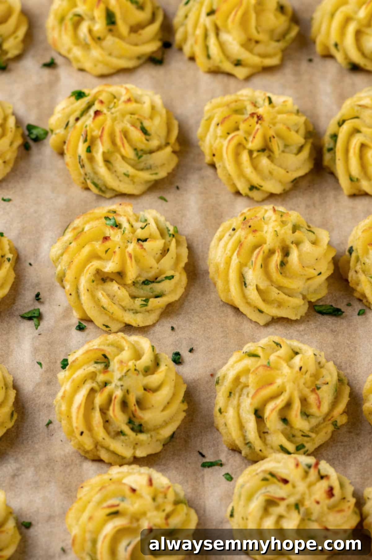 Baked vegan duchess potatoes arranged neatly on a parchment-lined sheet pan