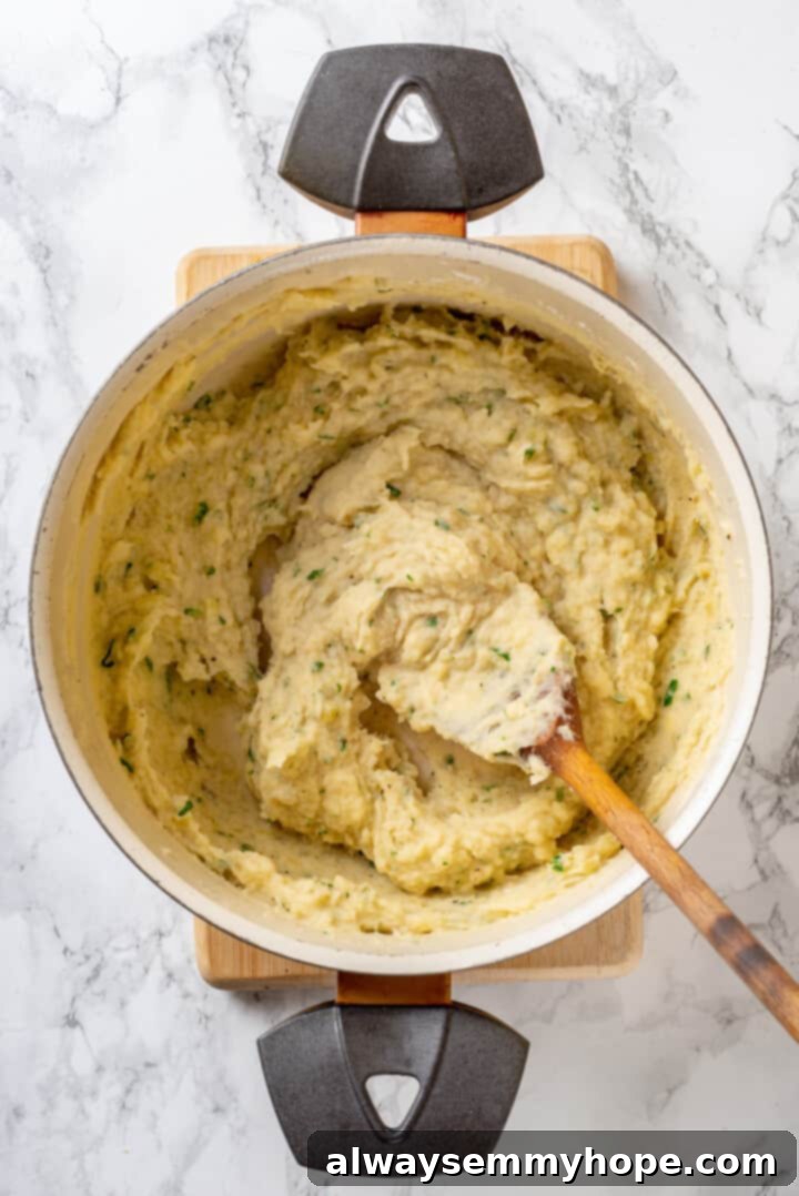 Pot containing smooth, well-mixed duchess potato mixture with a wooden spoon