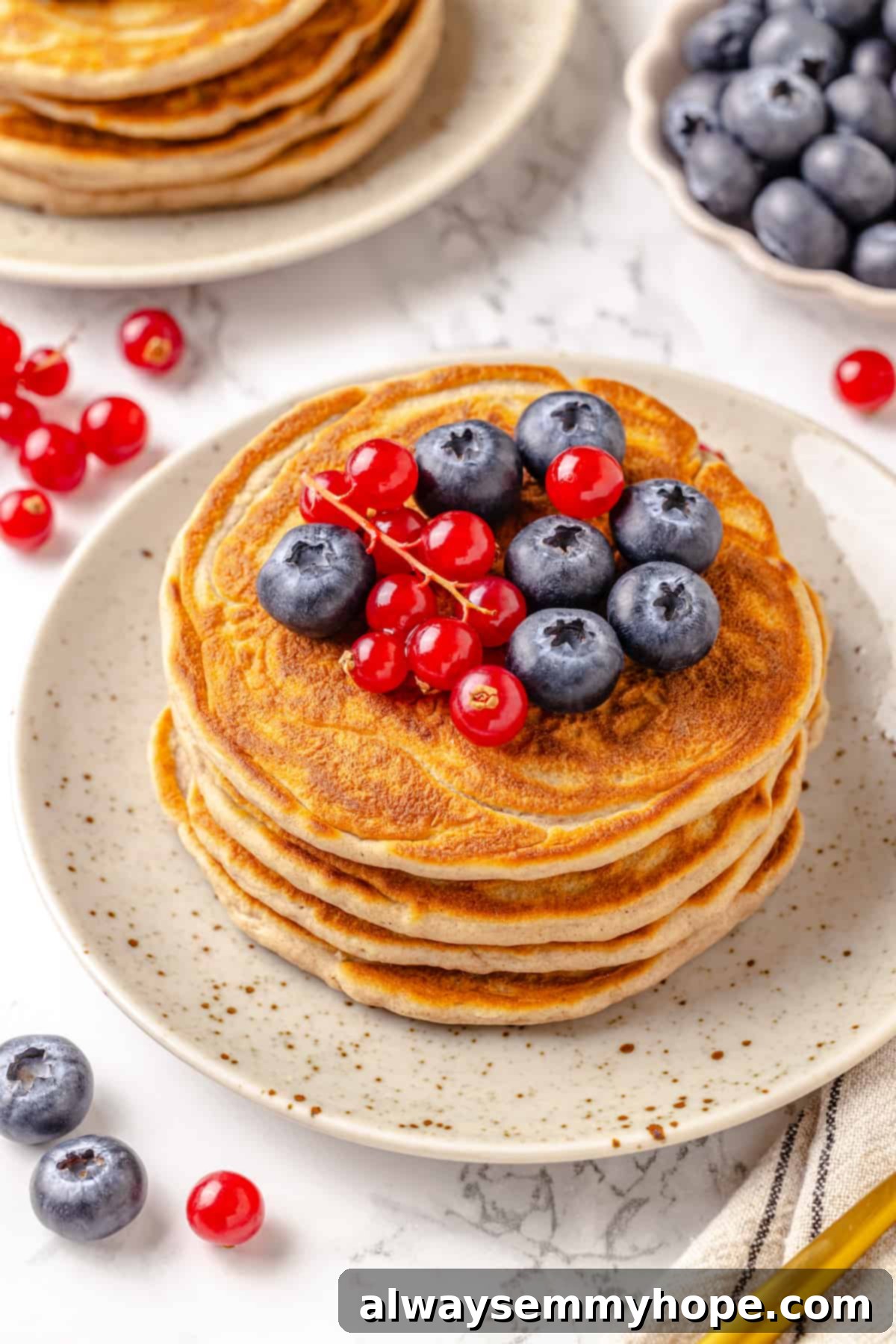Stack of protein pancakes on plate with fresh berries on top
