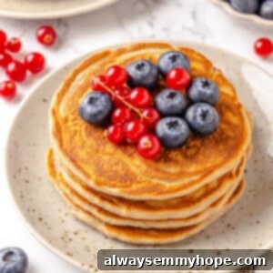 Stack of protein pancakes on plate with fresh berries on top