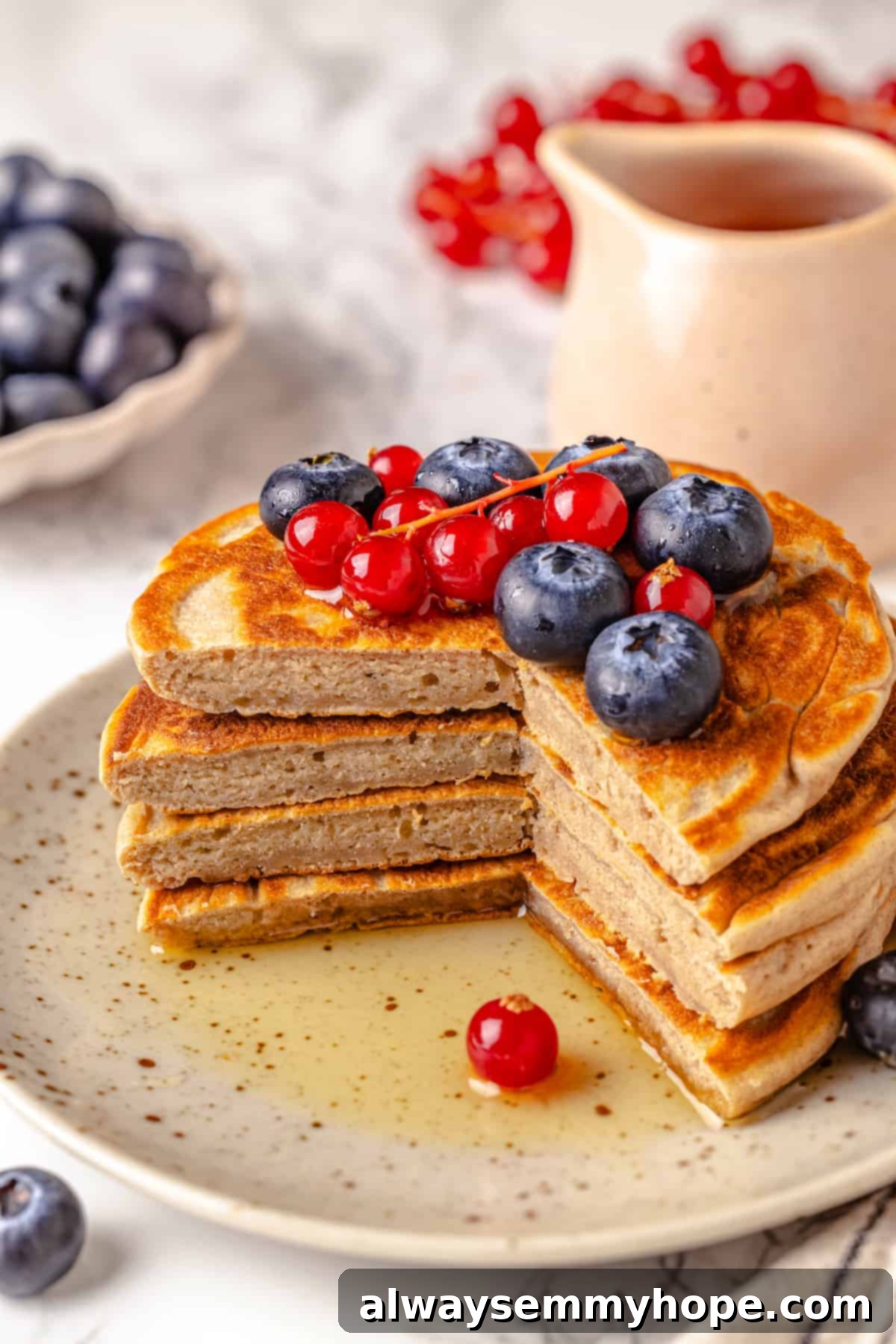 Stack of protein pancakes on plate, cut to show fluffy texture