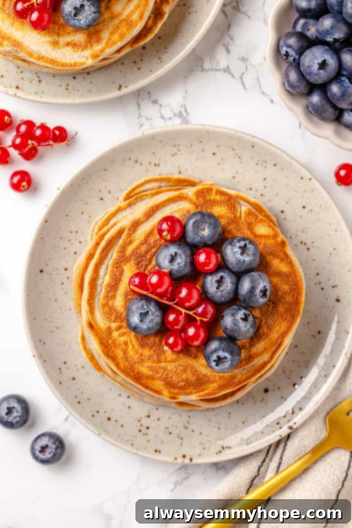 Overhead view of protein pancakes on plate with berries on top