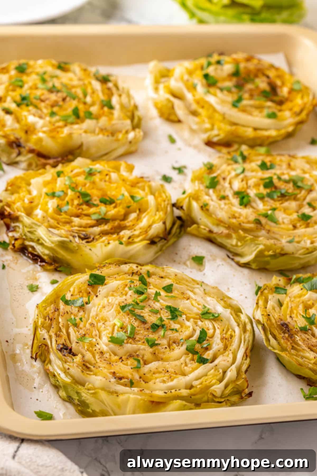 Roasted cabbage steaks freshly removed from the oven on a sheet pan, sprinkled with fresh parsley.