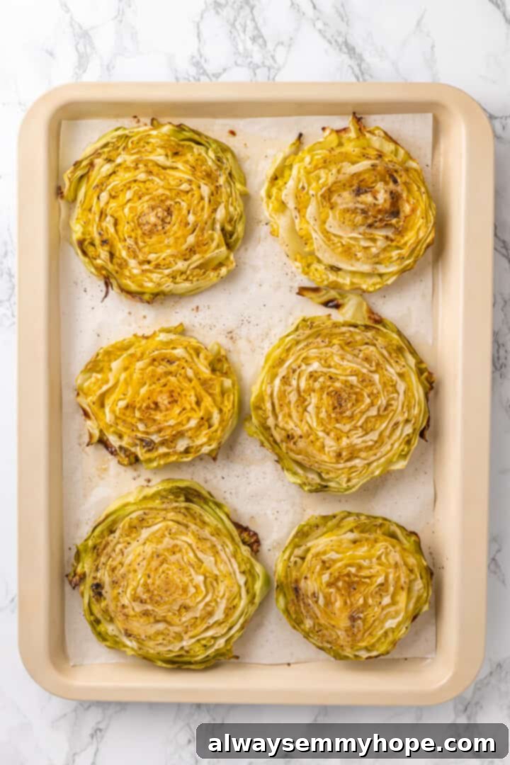 Overhead view of roasted cabbage steaks on a baking sheet, golden brown and tender, before garnishing.