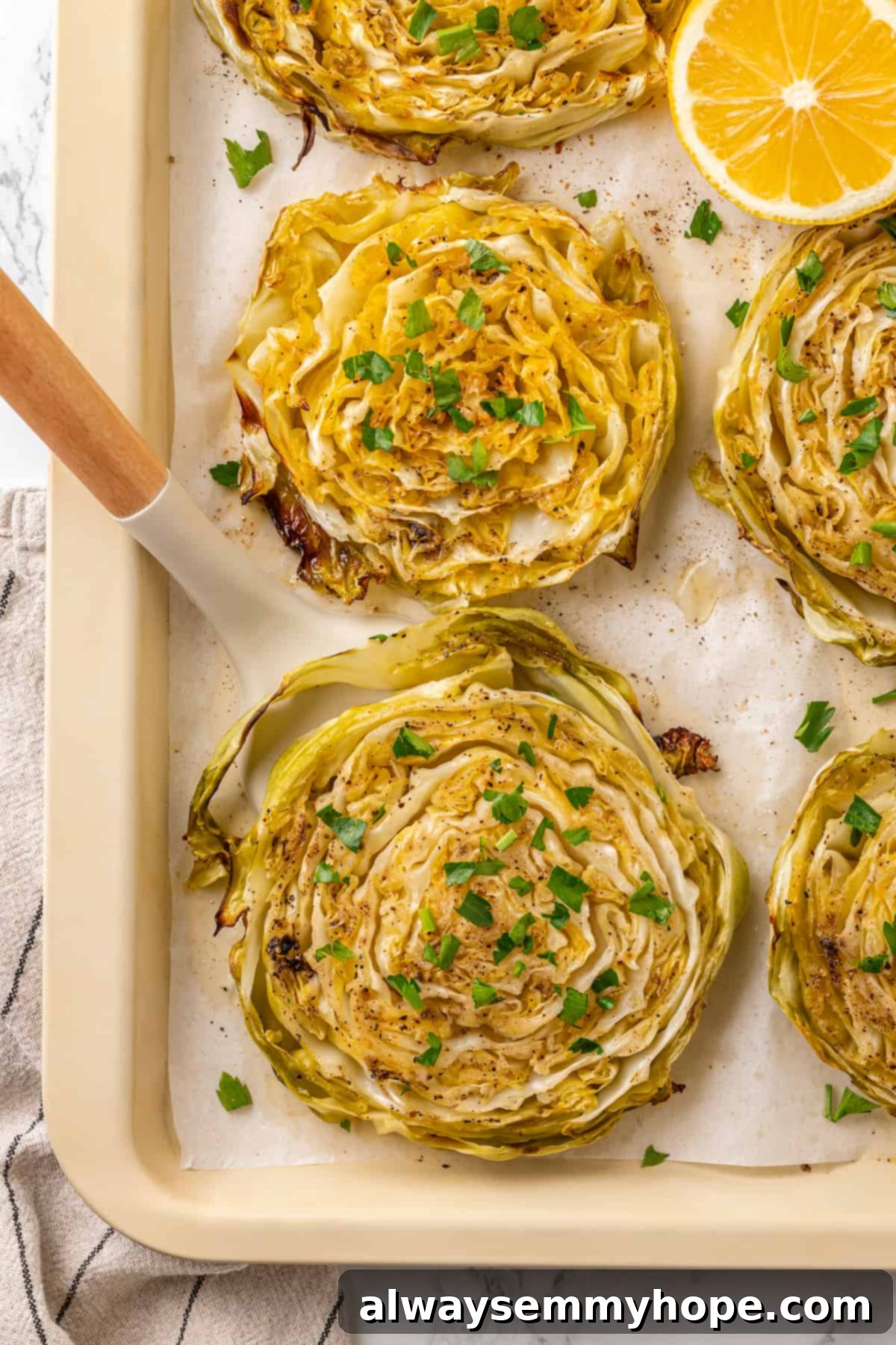 A spatula lifting a perfectly roasted cabbage steak from a baking pan, showing its golden-brown edges.