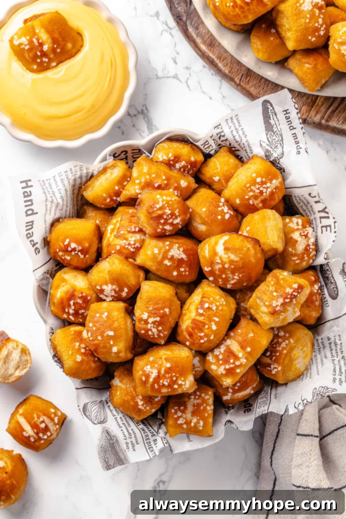Homemade vegan pretzel bites are the snackable sibling to regular soft pretzels! They're perfect for game day parties and easy to make too. A rustic basket overflowing with vegan pretzel bites, served alongside a bowl of creamy cheese dip, creating an inviting spread.