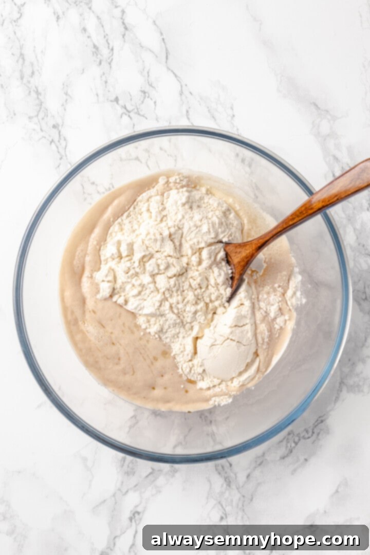 Homemade vegan pretzel bites are the snackable sibling to regular soft pretzels! They're perfect for game day parties and easy to make too. A wooden spoon stirring flour into a wet yeast mixture, gradually forming the pretzel dough.