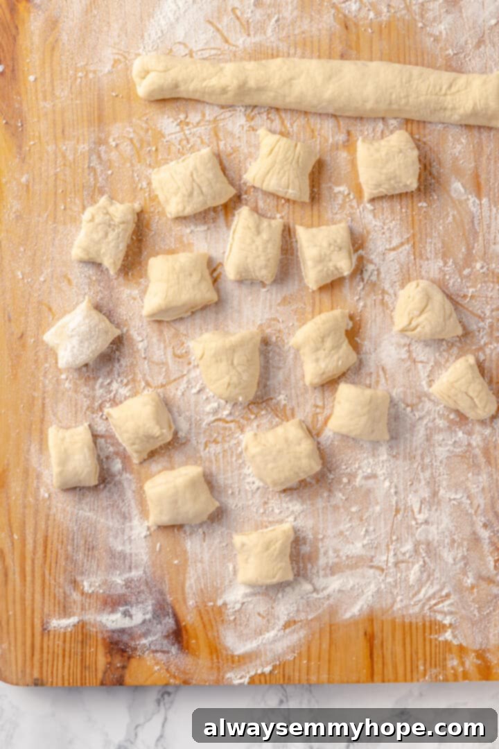 Homemade vegan pretzel bites are the snackable sibling to regular soft pretzels! They're perfect for game day parties and easy to make too. Pretzel dough being expertly cut into bite-sized pieces on a cutting board, preparing for the boiling step.