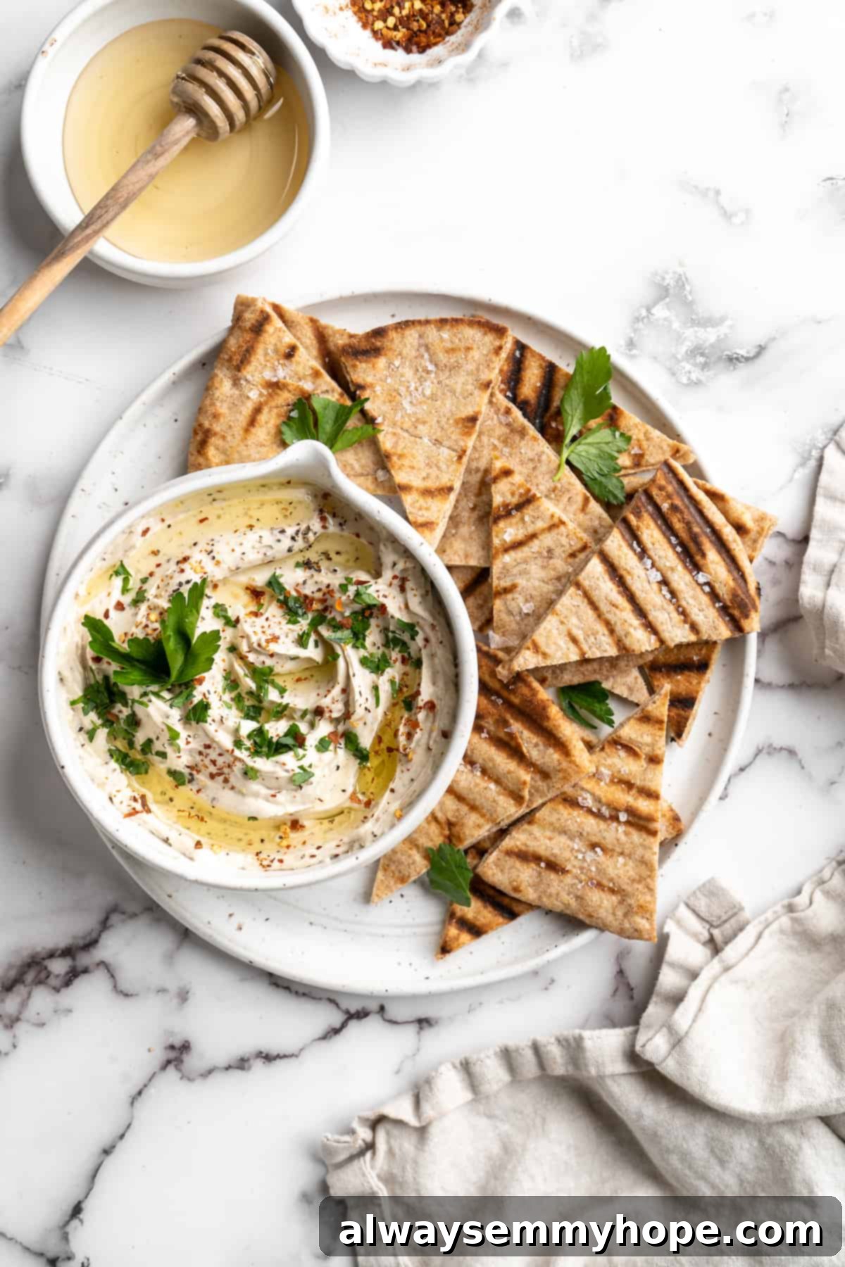 Overhead view of a beautifully presented vegan whipped feta dip in a rustic bowl, surrounded by perfectly grilled pita wedges on a serving platter.