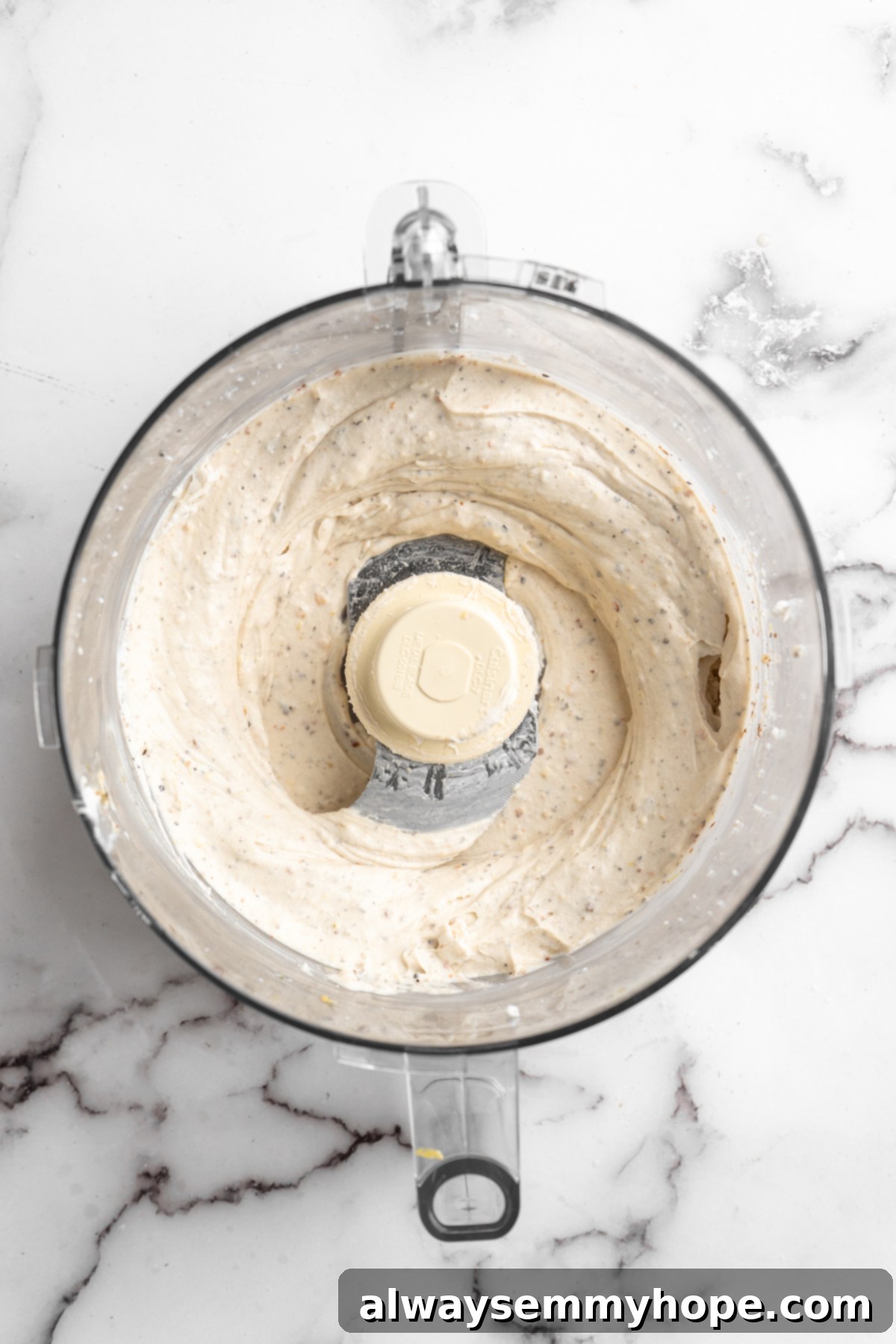 Overhead view of vegan whipped feta dip being processed in a food processor, showing the beginning stages of its creamy transformation.