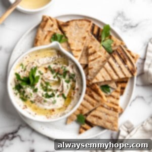 Overhead view of vegan whipped feta dip in bowl on platter of grilled pita wedges