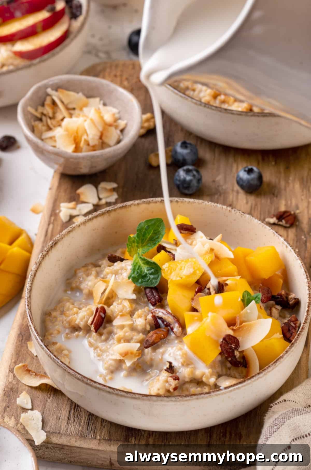 This Instant Pot steel-cut oats recipe is the easiest way to make hearty and creamy oatmeal for breakfast. Simple, hands-off recipe! Pouring plant milk into a bowl of mango Instant Pot steel-cut oats, showcasing a customizable consistency