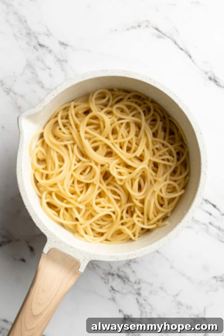 This lemon pasta recipe is light and flavourful, with bright lemon, plenty of garlic, and umami vegan Parmesan. An easy weeknight dinner! Overhead view of perfectly cooked spaghetti in a large pot, ready to be drained.