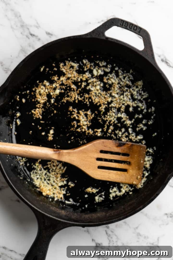 This lemon pasta recipe is light and flavourful, with bright lemon, plenty of garlic, and umami vegan Parmesan. An easy weeknight dinner! Overhead view of minced garlic being gently sautéed in olive oil in a skillet until fragrant.