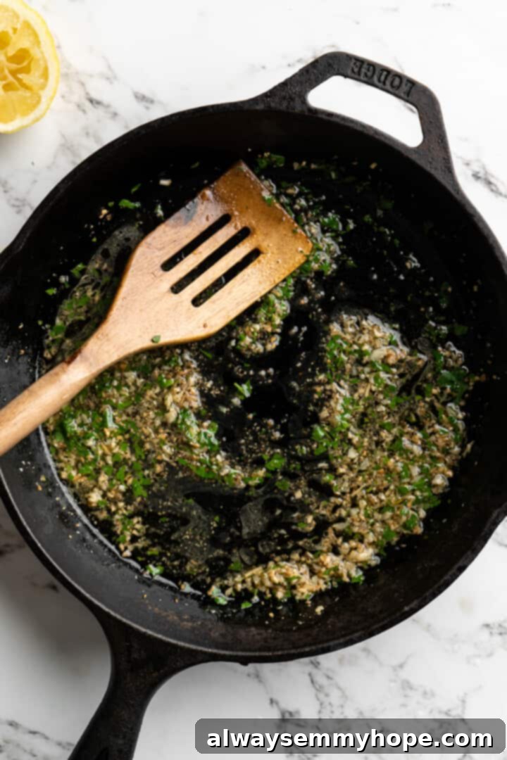 This lemon pasta recipe is light and flavourful, with bright lemon, plenty of garlic, and umami vegan Parmesan. An easy weeknight dinner! Overhead view of the lemon and garlic sauce simmering in a cast iron skillet.