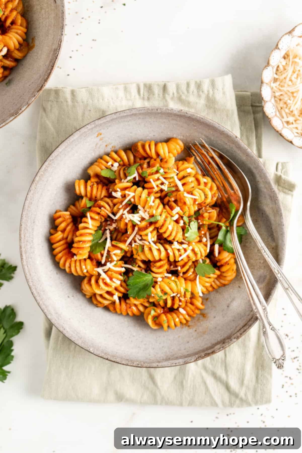 You won't believe how easy it is to make homemade marinara sauce! This recipe is ready to eat in 15 minutes. No peeling or chopping tomatoes! A bowl of rotini pasta coated in vibrant homemade marinara sauce, garnished with grated Parmesan and fresh parsley.