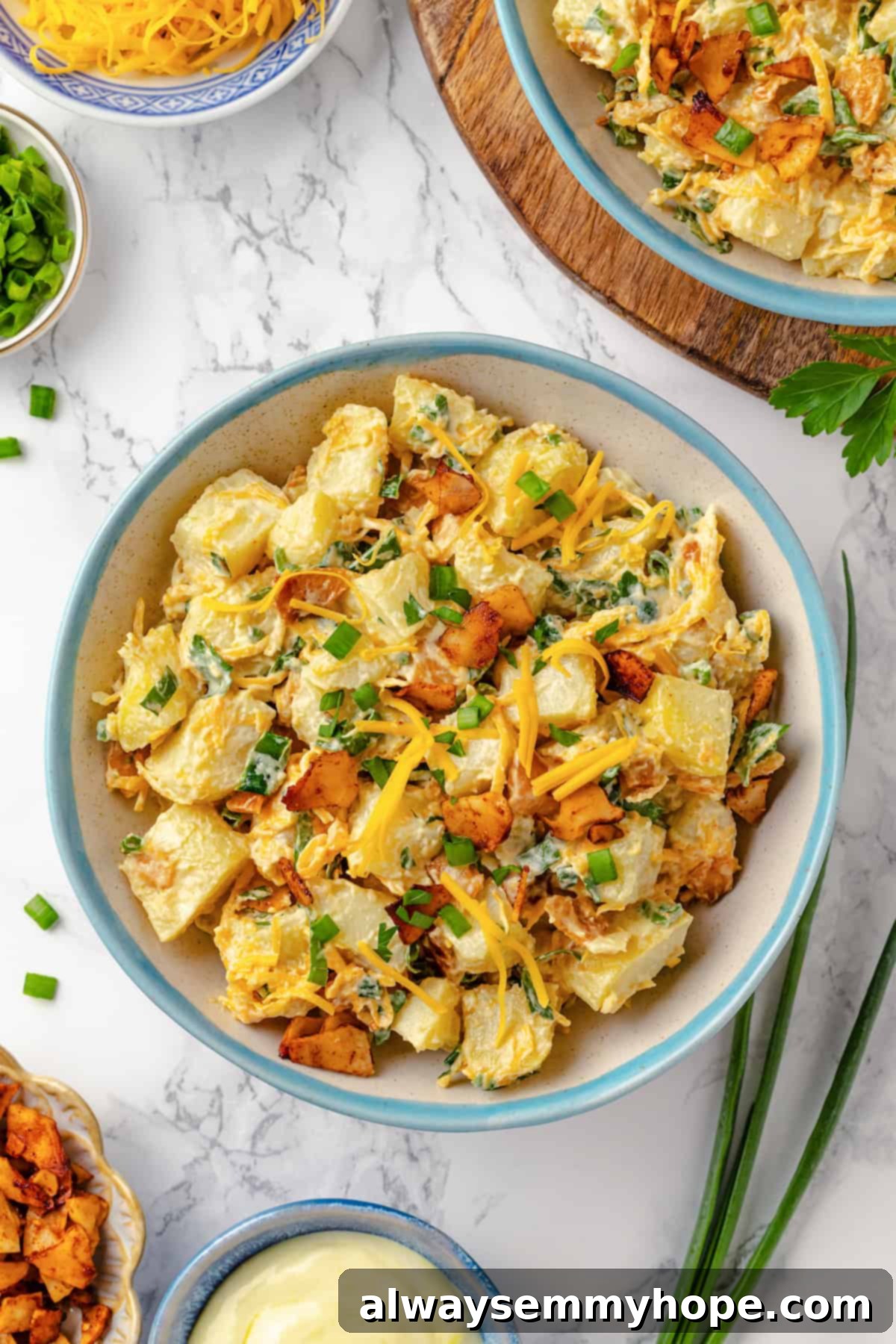 A generous serving of vegan loaded potato salad in a rustic bowl, topped with extra vegan bacon crumbles and shredded vegan cheddar, highlighting its rich and inviting appearance.