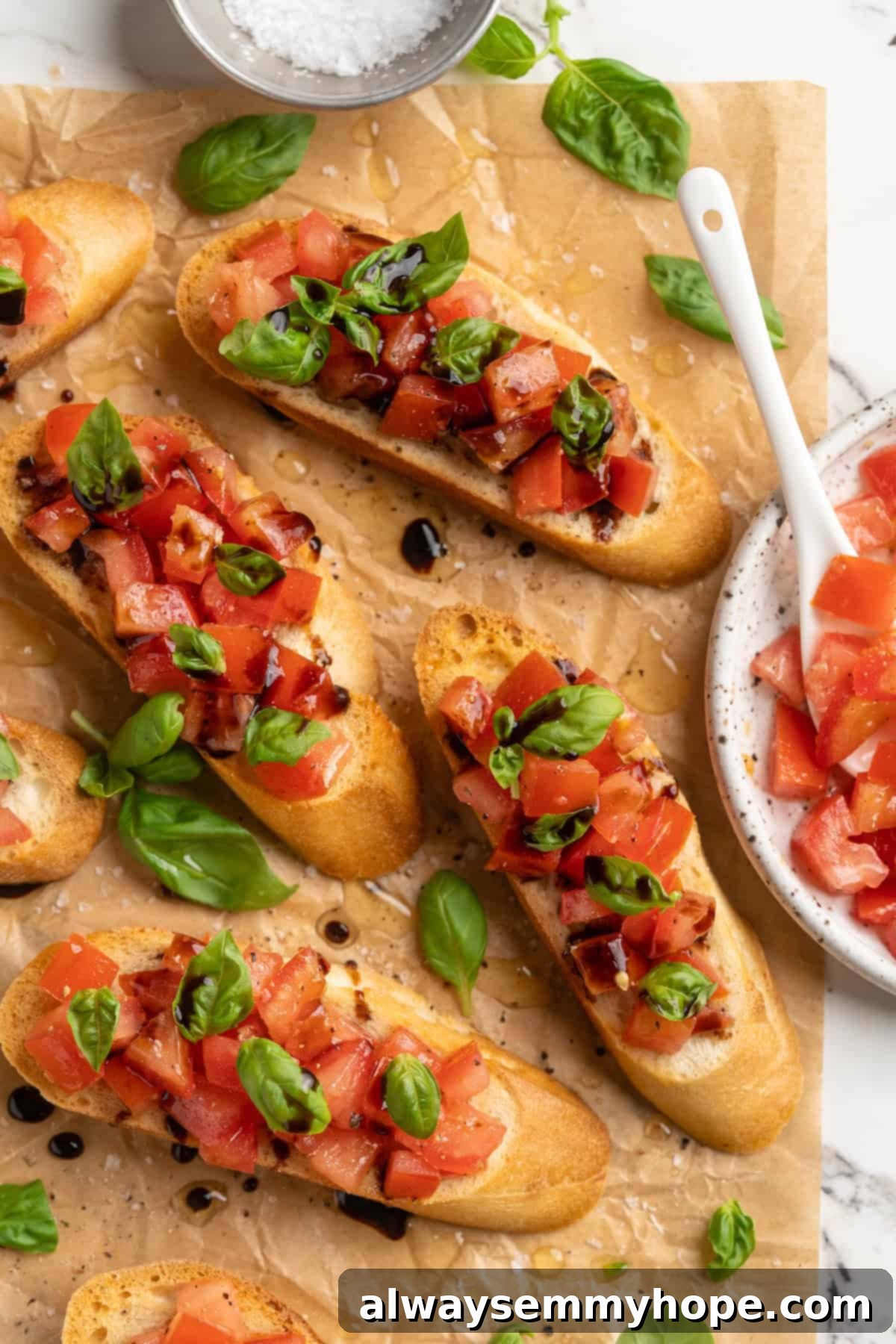 Overhead view of classic bruschetta on parchment paper with fresh basil garnish, emphasizing its freshness and appeal as an appetizer.