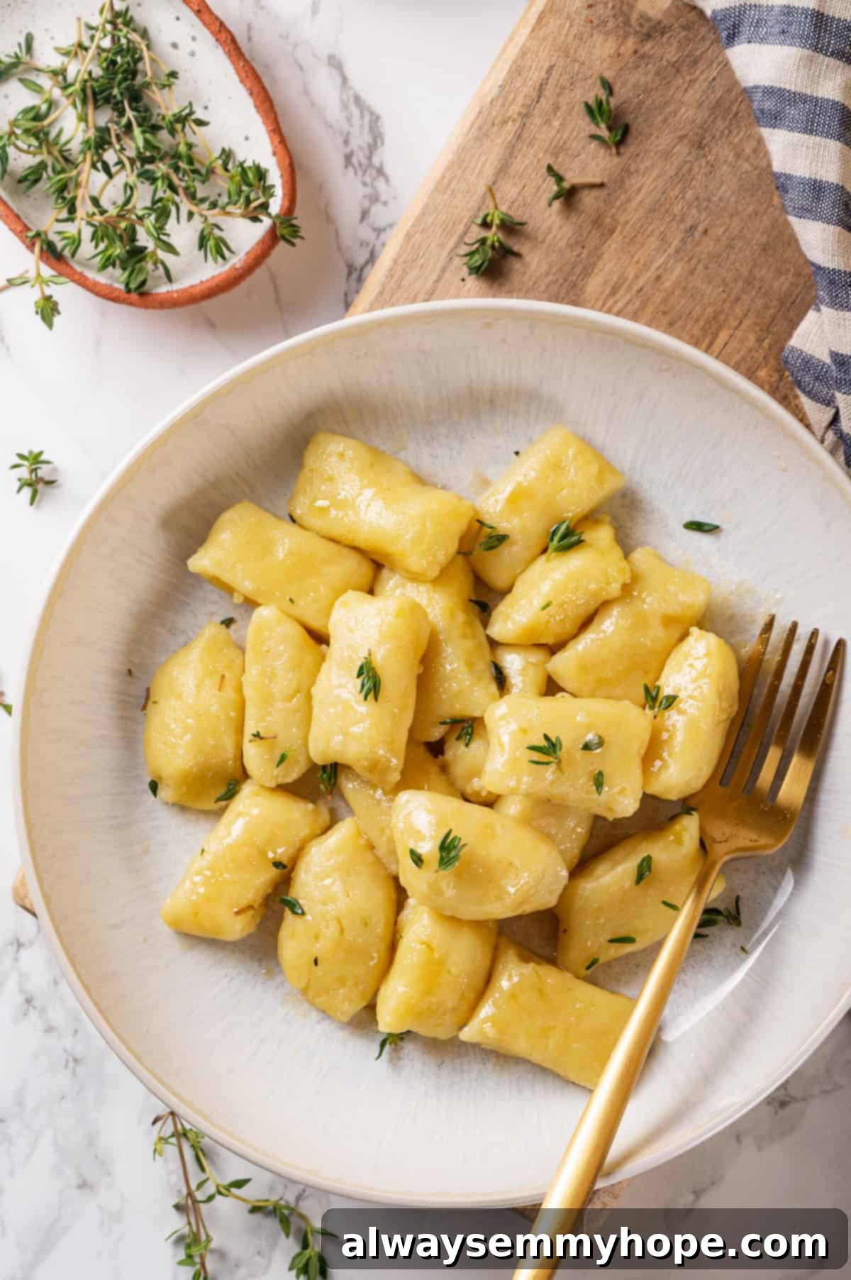 Top-down view of vegan gnocchi in bowl with thyme and butter sauce