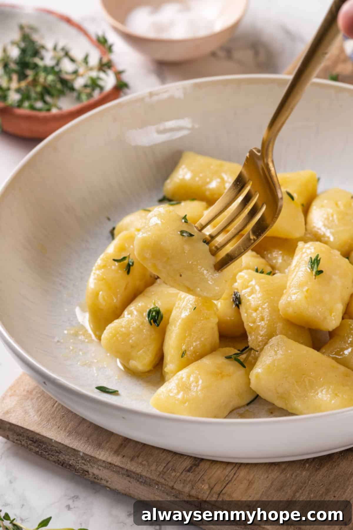 Fork picking up homemade gnocchi with fresh thyme for garnish
