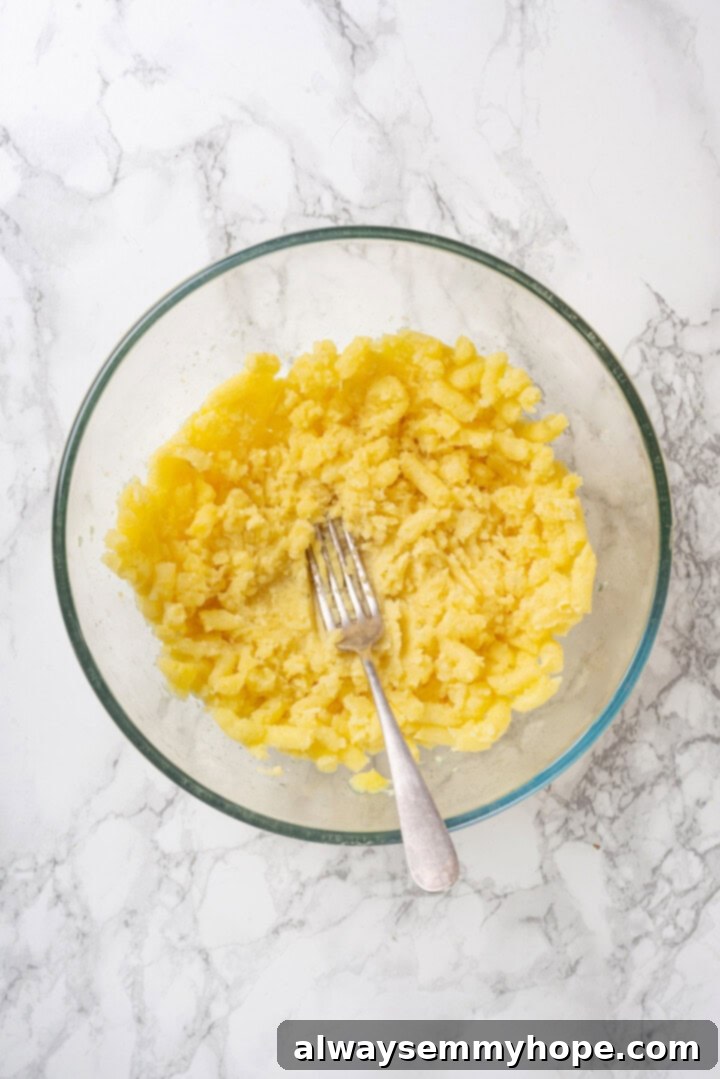 Fork mashing potatoes in glass bowl