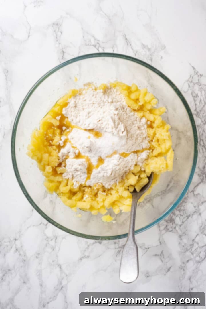 Potatoes, flour, salt, and oil in glass bowl with spoon