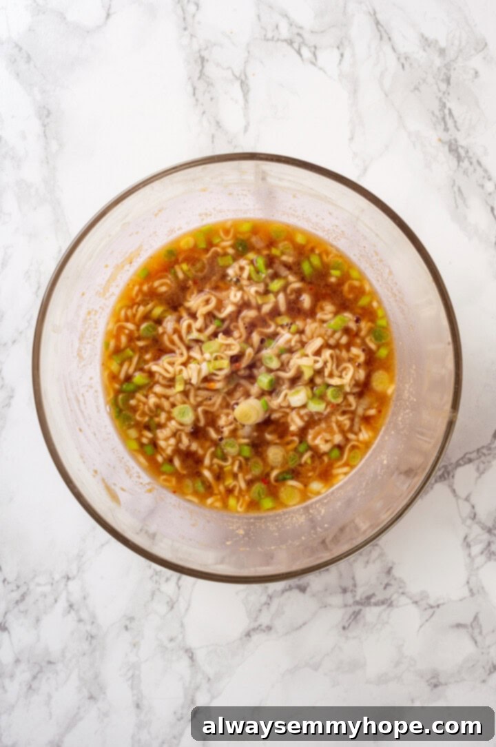 Overhead view of instant ramen noodles added to the prepared peanut sauce broth in a bowl.