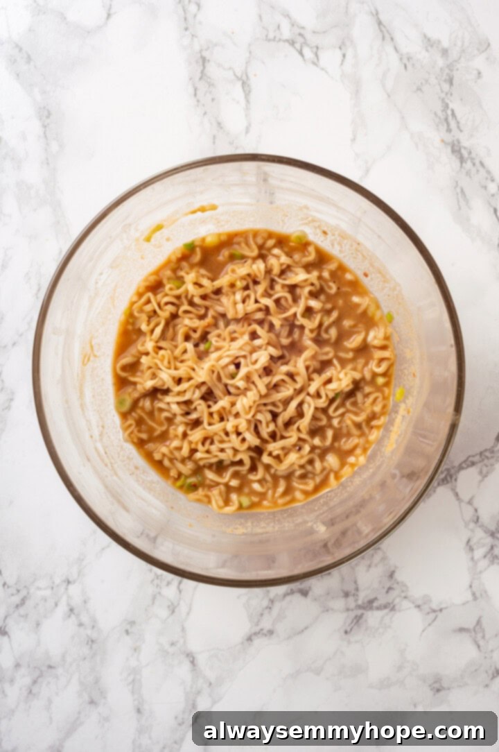 Overhead view of perfectly cooked ramen noodles tossed in a rich peanut sauce, served in a bowl.