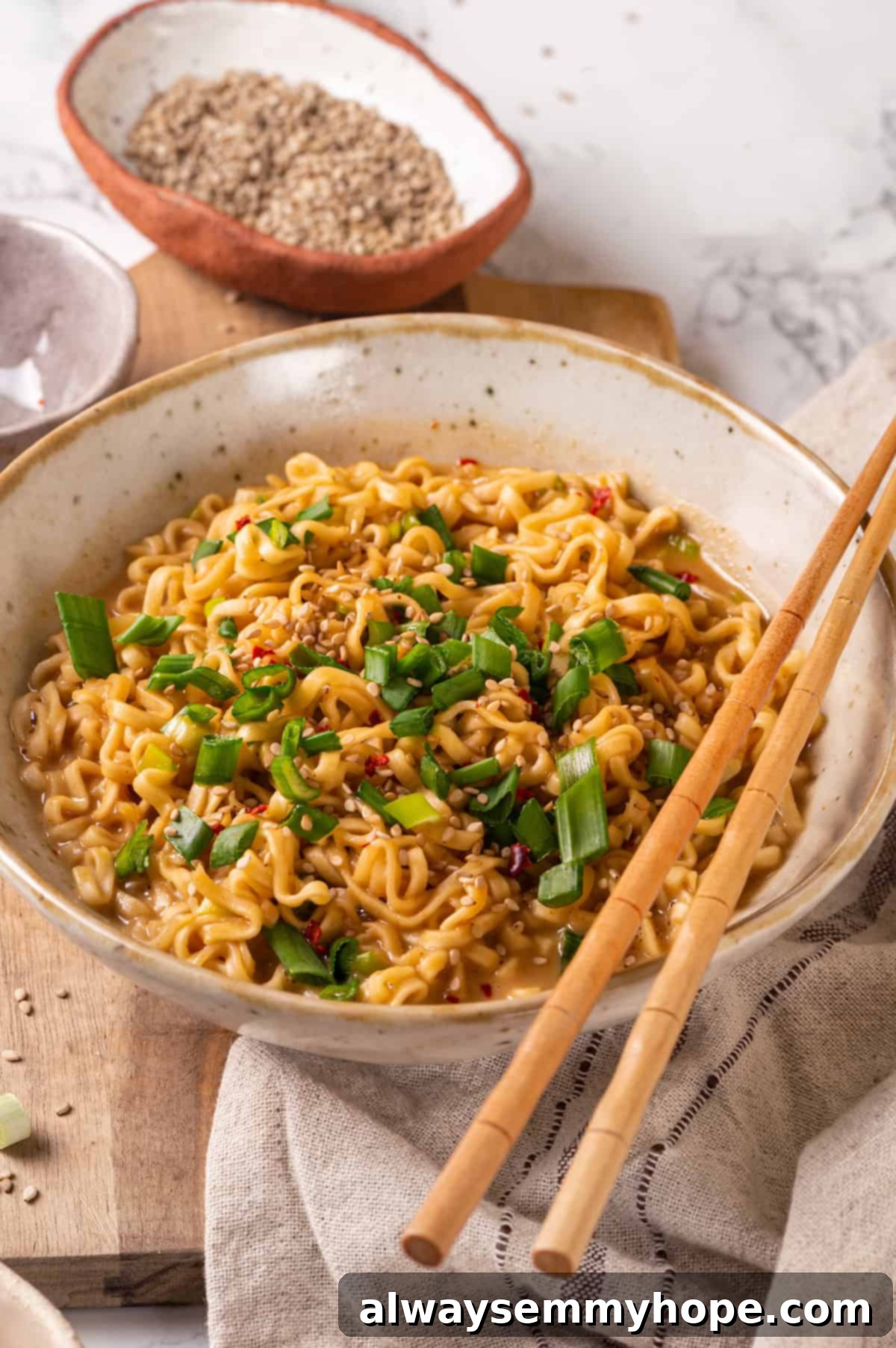 Close-up shot of vegan peanut butter ramen in a bowl with chopsticks, showing the rich sauce and scallion garnish.