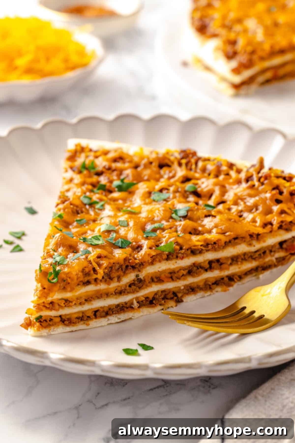 With layers of seasoned taco meat, plant-based cheese, and tortillas, this easy taco bake recipe is sure to please the whole family! A perfectly portioned slice of layered vegan taco bake on a white plate, showcasing its vibrant layers of plant-based meat, melted cheese, and tortillas.