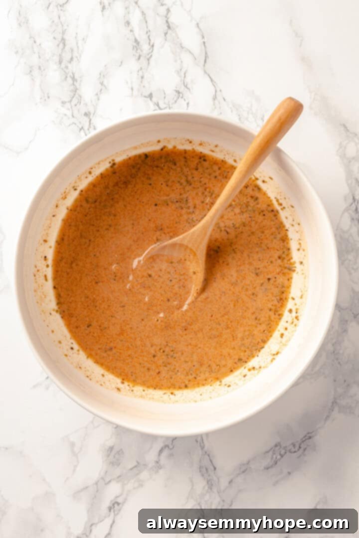 With layers of seasoned taco meat, plant-based cheese, and tortillas, this easy taco bake recipe is sure to please the whole family! Overhead view of creamy, orange-hued sauce for taco bake in a mixing bowl.