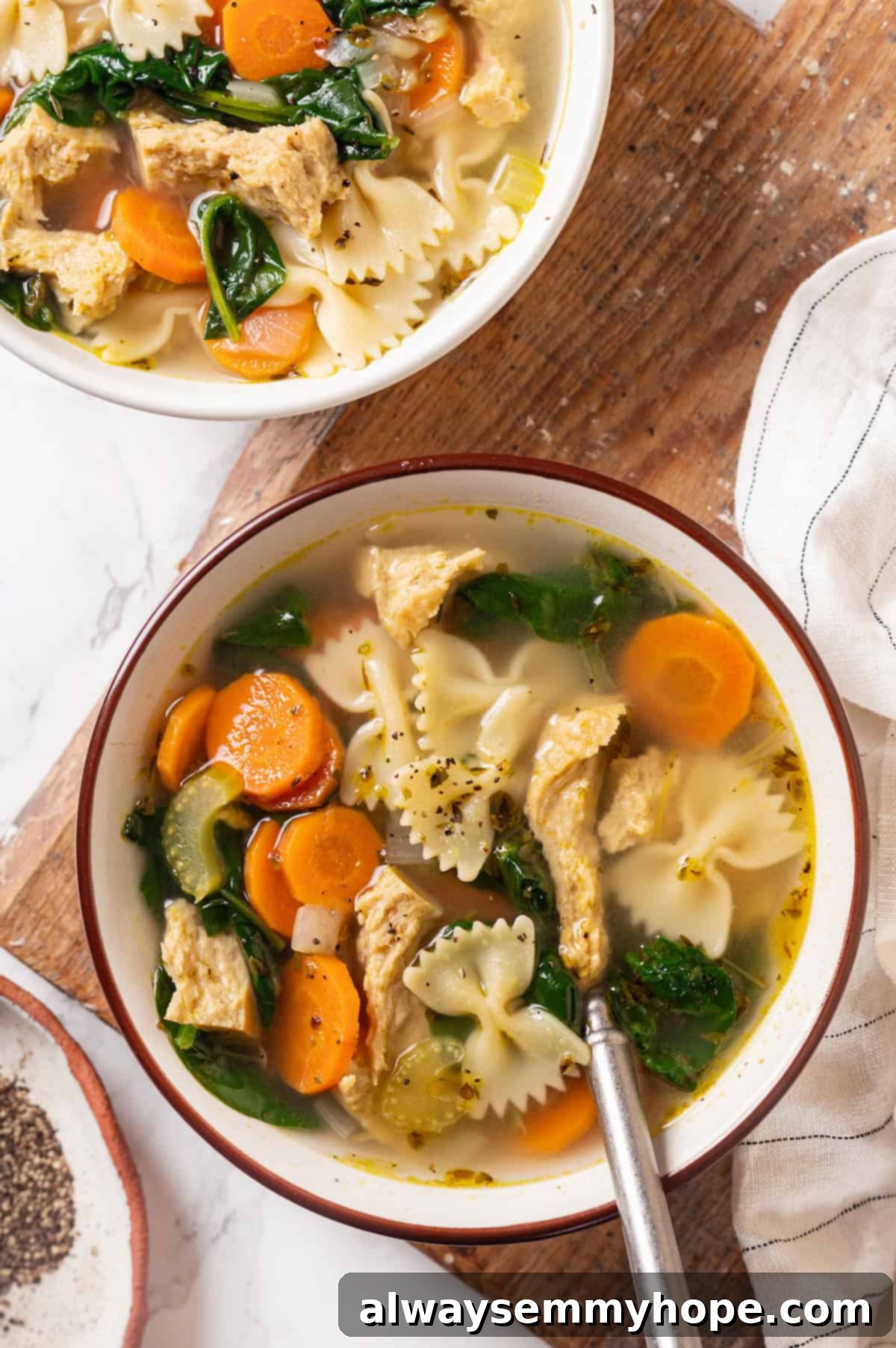 Overhead view of two bowls of vegan chicken noodle soup, garnished with fresh parsley, ready to be served.