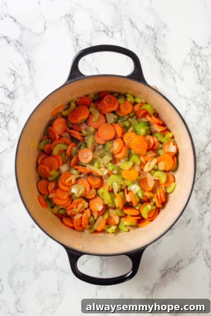 Sauteed mixture of onions, carrots, and celery (mirepoix) in a pot for vegan chicken noodle soup.