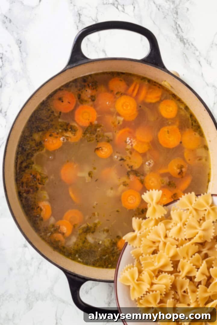 Adding dry bowtie pasta directly into a pot of simmering vegan chicken noodle soup.