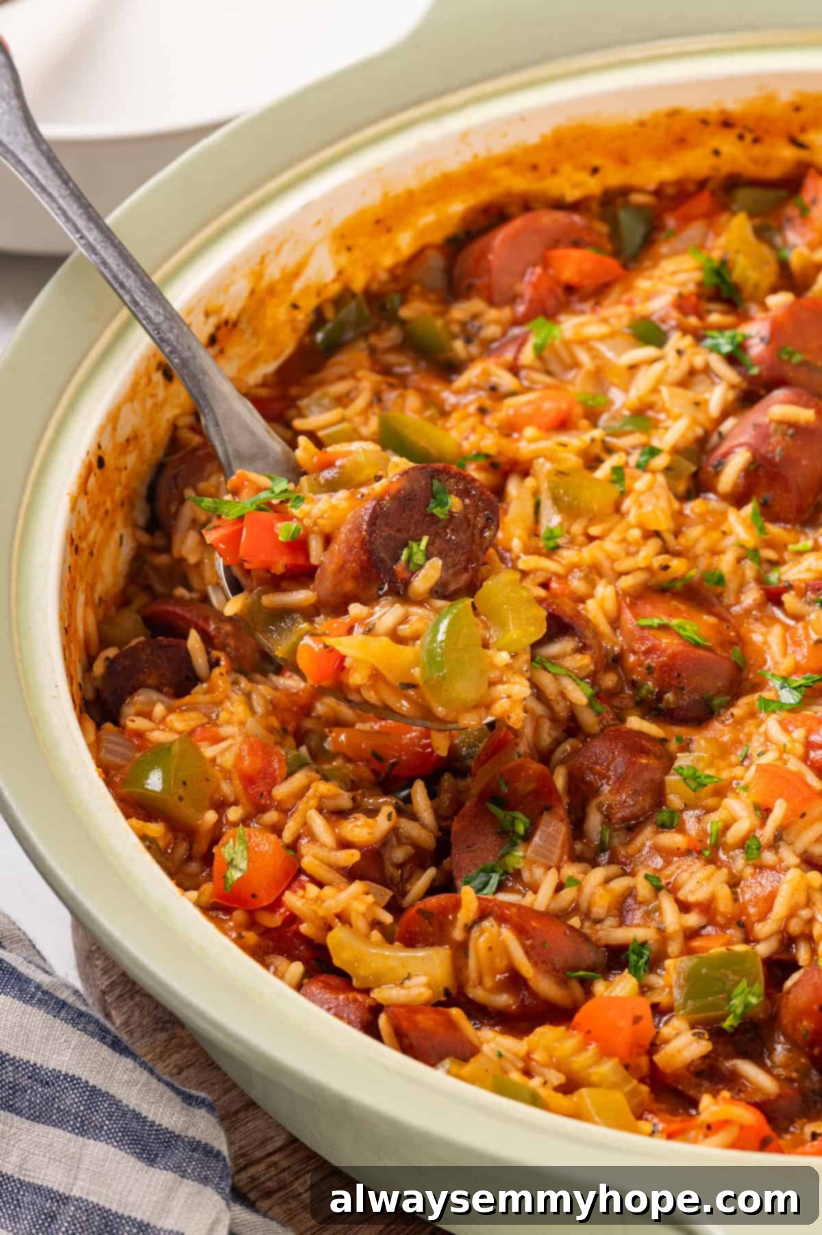 Vegan jambalaya recipe is comfort food Cajun style! With rice, veggies and plant-based sausage, this is a meal that’s flavourful and hearty. Skillet of vegan jambalaya with a serving spoon, ready to be dished out