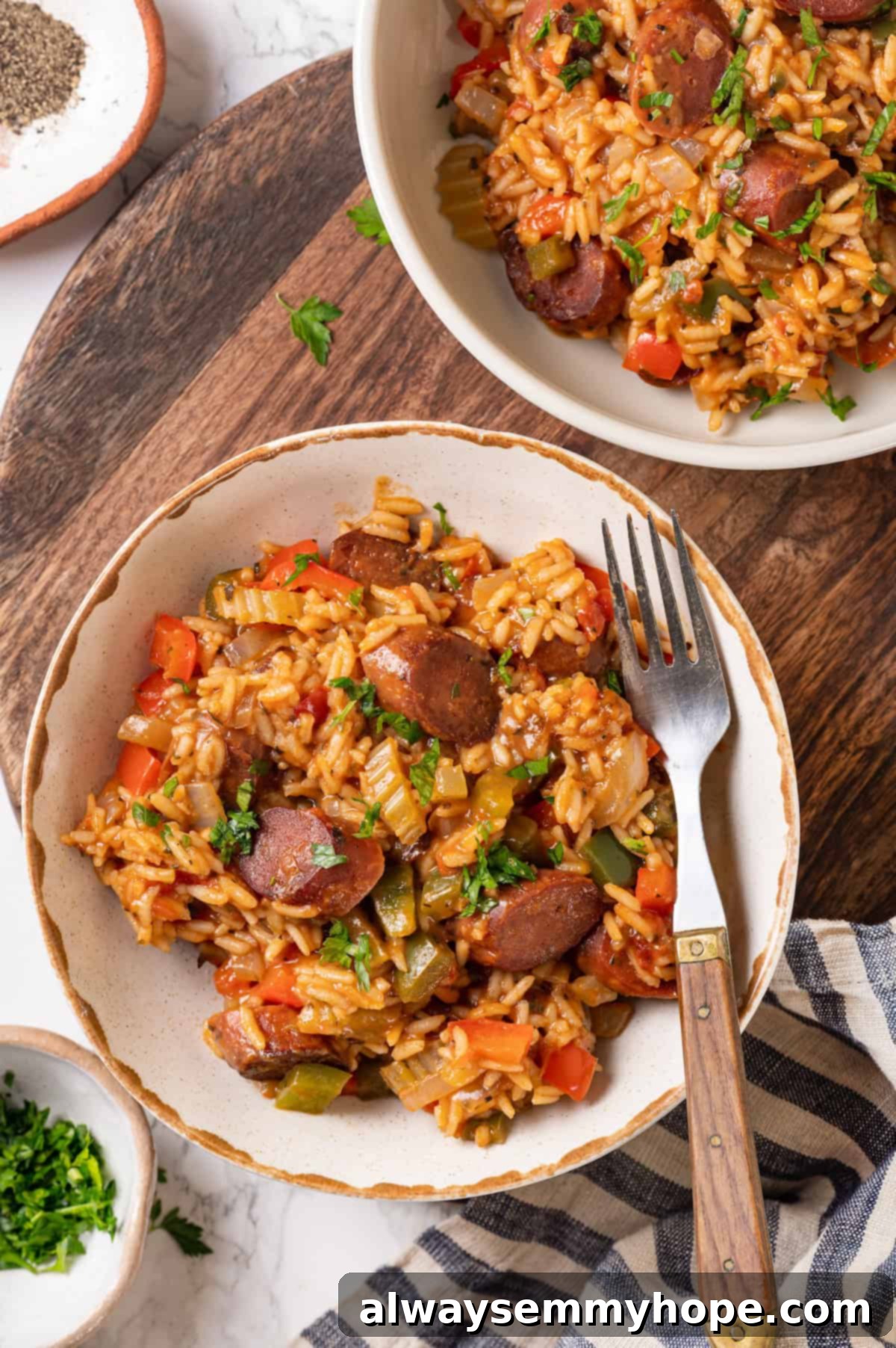 Vegan jambalaya recipe is comfort food Cajun style! With rice, veggies and plant-based sausage, this is a meal that’s flavourful and hearty. Overhead view of vegan jambalaya served in two bowls, garnished with fresh herbs