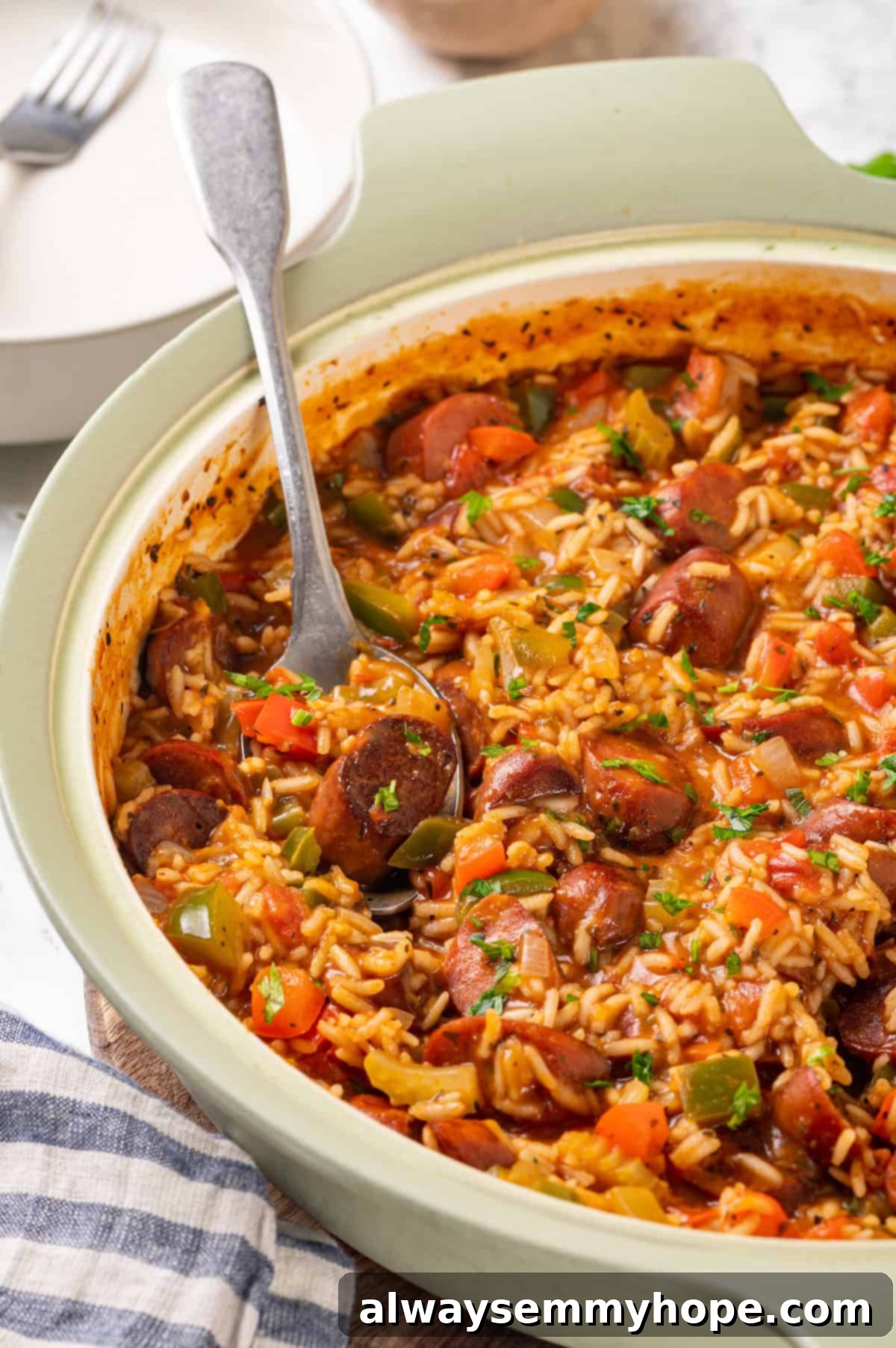 Vegan jambalaya recipe is comfort food Cajun style! With rice, veggies and plant-based sausage, this is a meal that’s flavourful and hearty. Spoonful of vegan jambalaya in skillet, highlighting the texture of rice and sausage