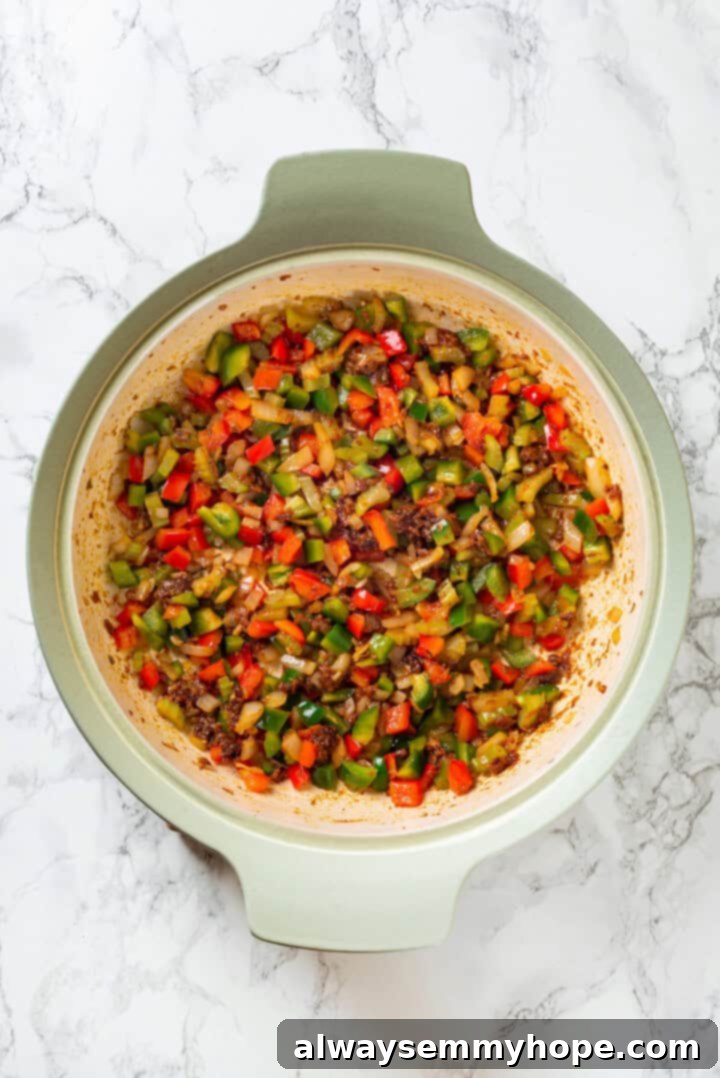 Vegan jambalaya recipe is comfort food Cajun style! With rice, veggies and plant-based sausage, this is a meal that’s flavourful and hearty. Overhead view of sauteed onions, bell peppers, and celery in skillet