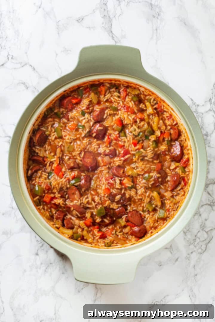 Vegan jambalaya recipe is comfort food Cajun style! With rice, veggies and plant-based sausage, this is a meal that’s flavourful and hearty. Overhead view of vegan jambalaya simmering in a skillet, rice absorbing liquid
