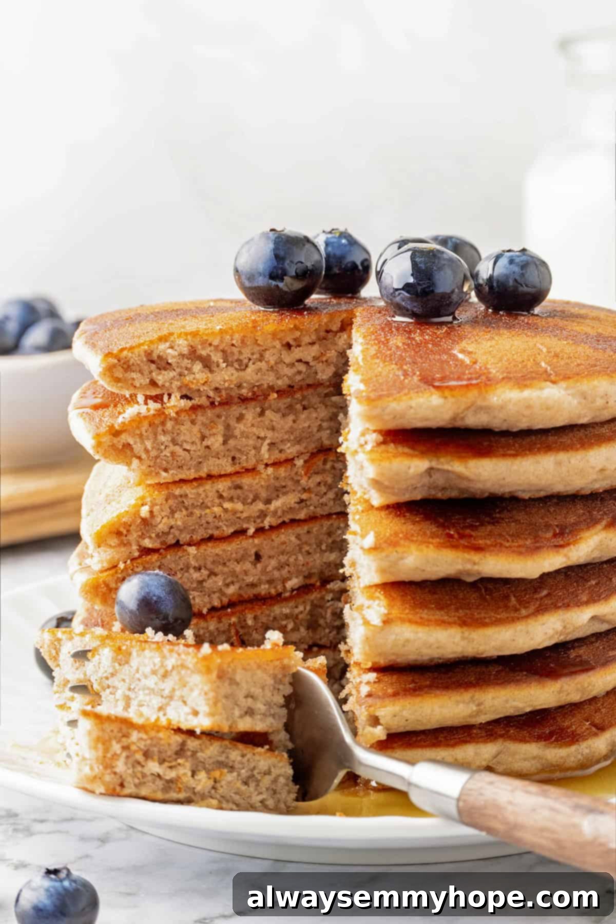 Stack of fluffy vegan buckwheat pancakes with a wedge cut out, showing their thick and airy texture, ready for syrup