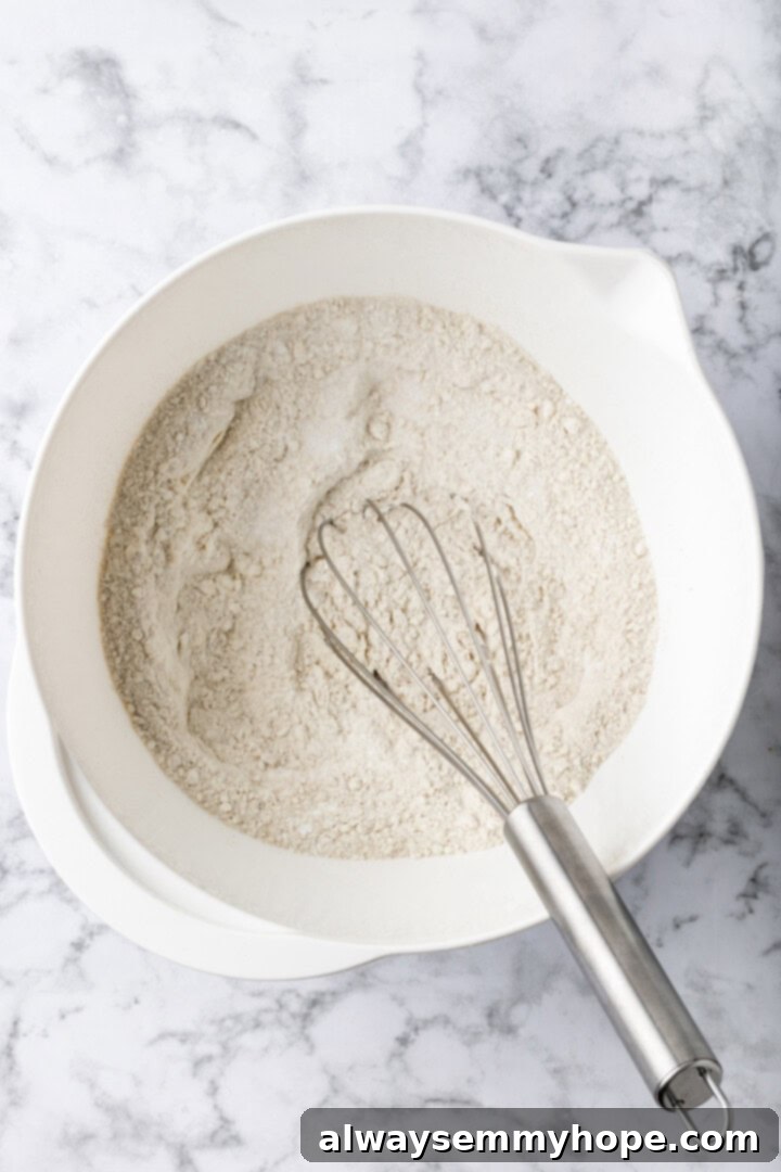 Overhead view of dry ingredients for buckwheat pancakes being whisked in a mixing bowl