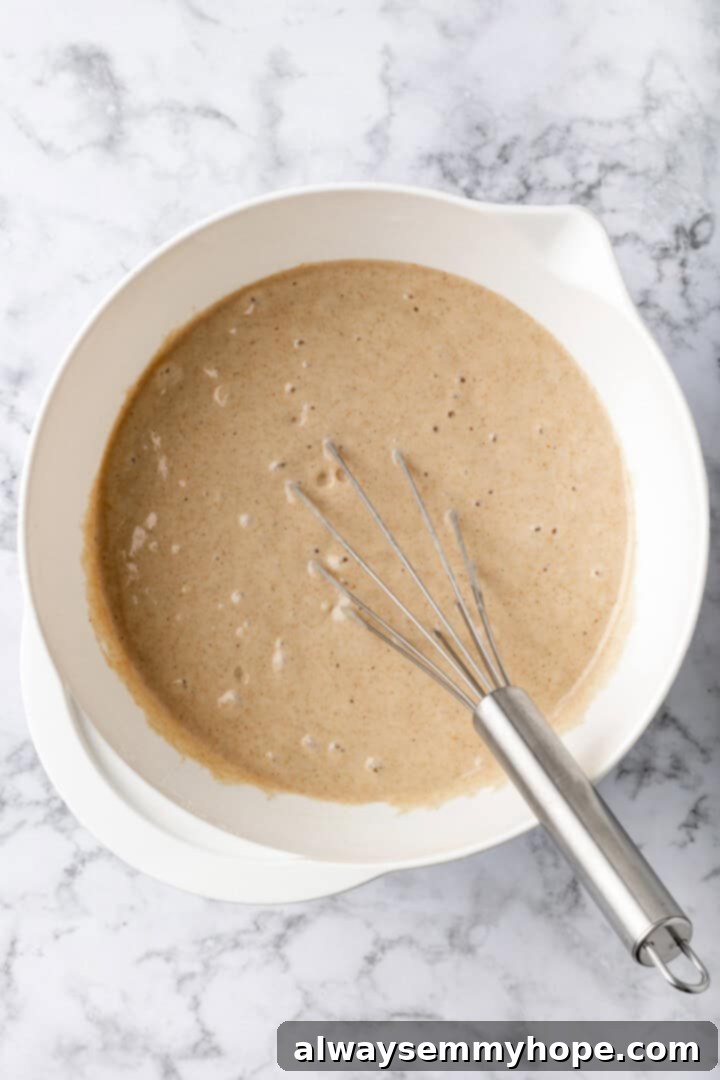 Overhead view of smooth vegan buckwheat pancake batter in a mixing bowl with a whisk