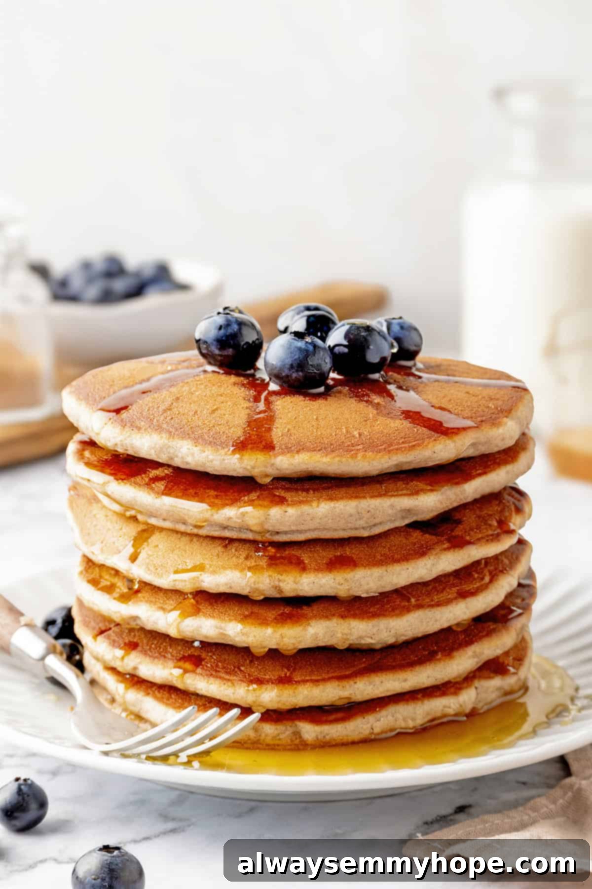 A perfectly stacked plate of fluffy vegan buckwheat pancakes with a fork, ready to be enjoyed