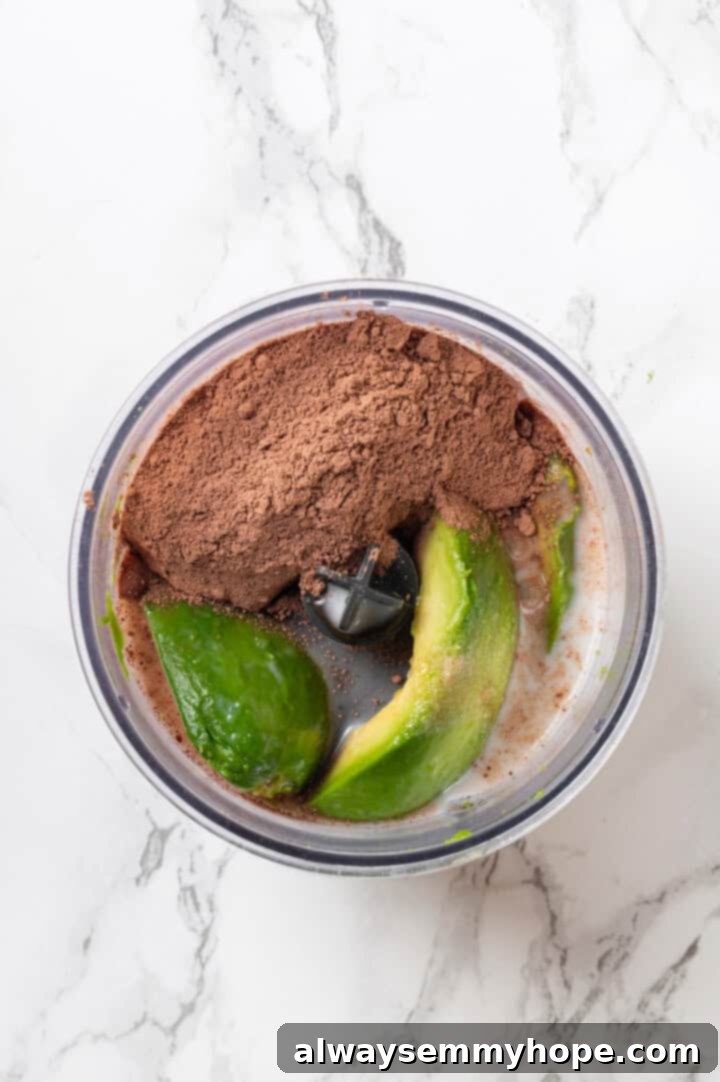 This easy avocado chocolate mousse recipe is rich, creamy, and oh-so-decadent—and you will never guess that the main ingredient is avocado! All the avocado chocolate mousse ingredients are added into a food processor, ready for blending.