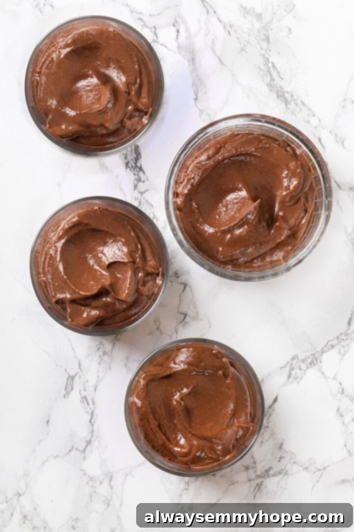 This easy avocado chocolate mousse recipe is rich, creamy, and oh-so-decadent—and you will never guess that the main ingredient is avocado! Four glass ramekins filled with avocado chocolate mousse, ready for chilling and serving.