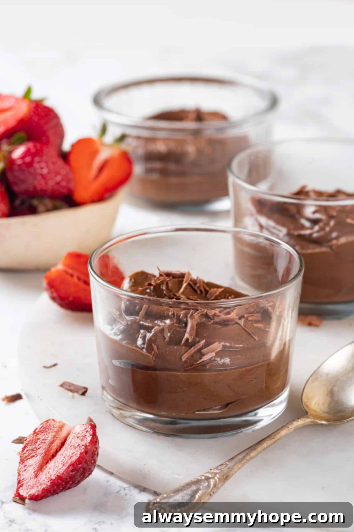 This easy avocado chocolate mousse recipe is rich, creamy, and oh-so-decadent—and you will never guess that the main ingredient is amazing! Three elegant ramekins of avocado chocolate mousse, beautifully topped with delicate chocolate shavings, ready to be served.
