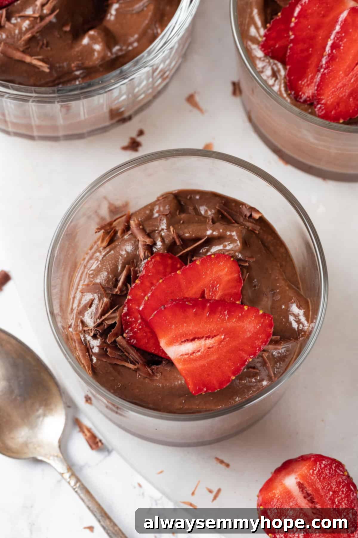 This easy avocado chocolate mousse recipe is rich, creamy, and oh-so-decadent—and you will never guess that the main ingredient is avocado! An overhead view of a glass ramekin filled with rich chocolate avocado mousse, elegantly garnished with fresh strawberry slices.